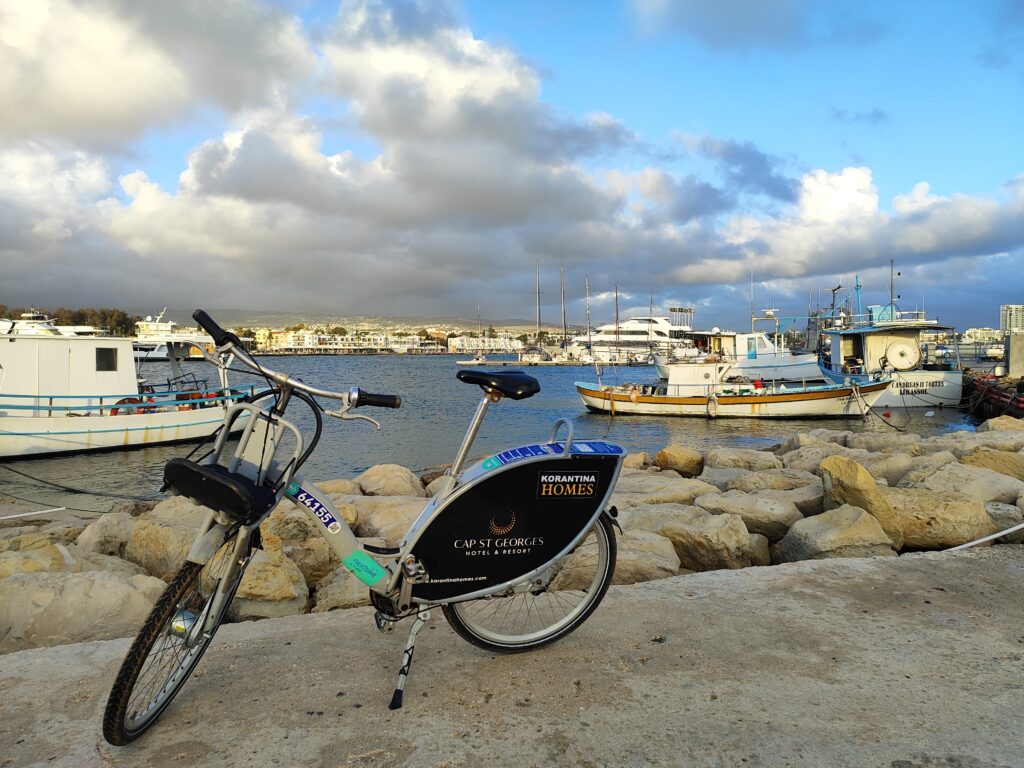 Rower miejski Nextbike Cyprus zaparkowany przy nabrzeżu w porcie Pafos z widokiem na łodzie