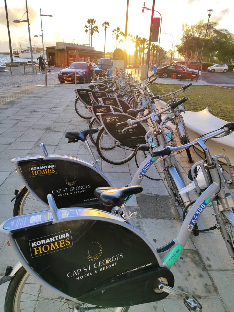 Rowery miejskie Nextbike w Pafos na Cyprze – stacja przy nadmorskiej promenadzie i palmach