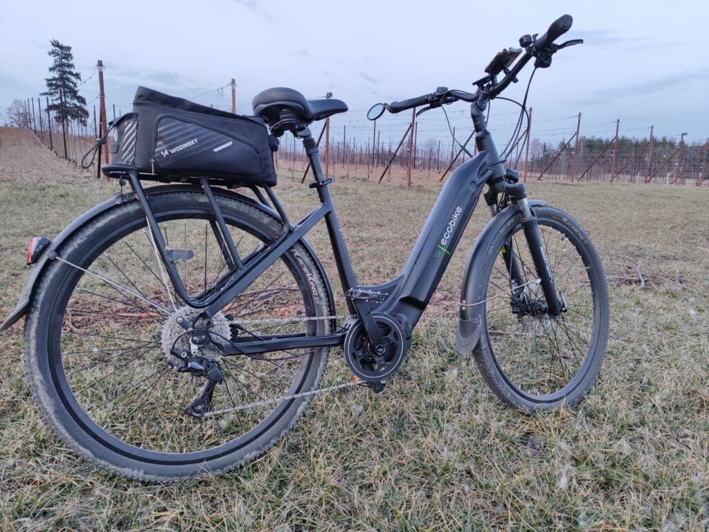 Ecobike D2 City Black rower elektryczny trekkingowy z silnikiem centralnym Bafang M420, widok z boku, torba na bagażniku, jazda rekreacyjna po terenie wiejskim