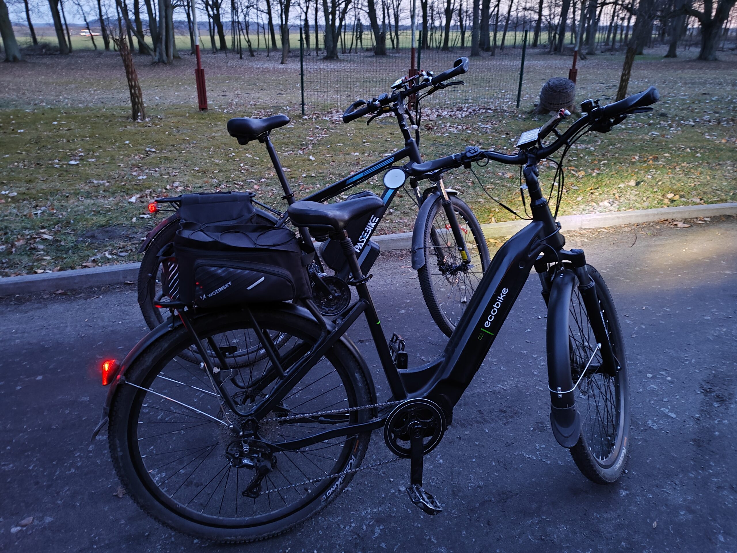Rower elektryczny Pasebike C29 Pro z torbą na bagażniku stojący obok drugiego e-bike na drodze