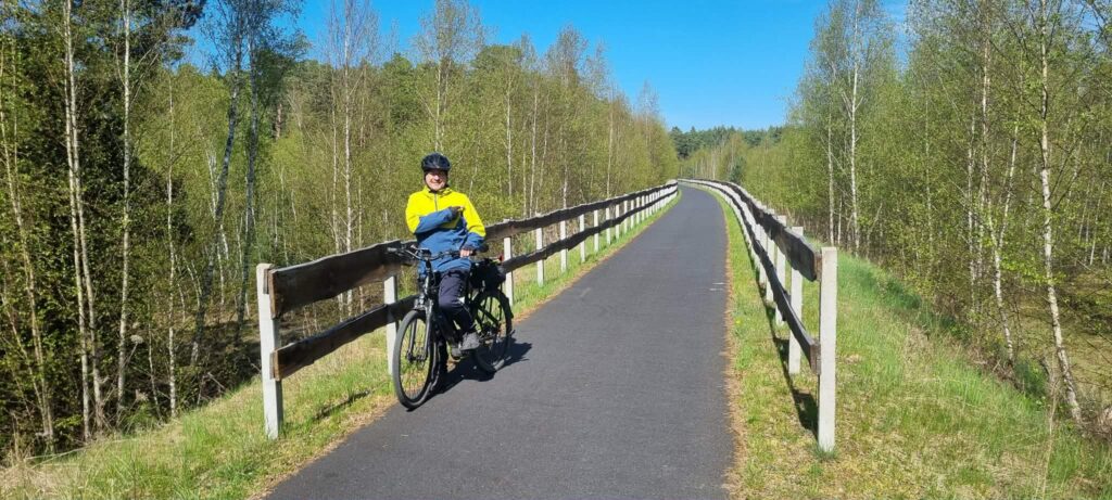 Asfaltowa droga rowerowa z charakterystycznymi drewnianymi barierkami